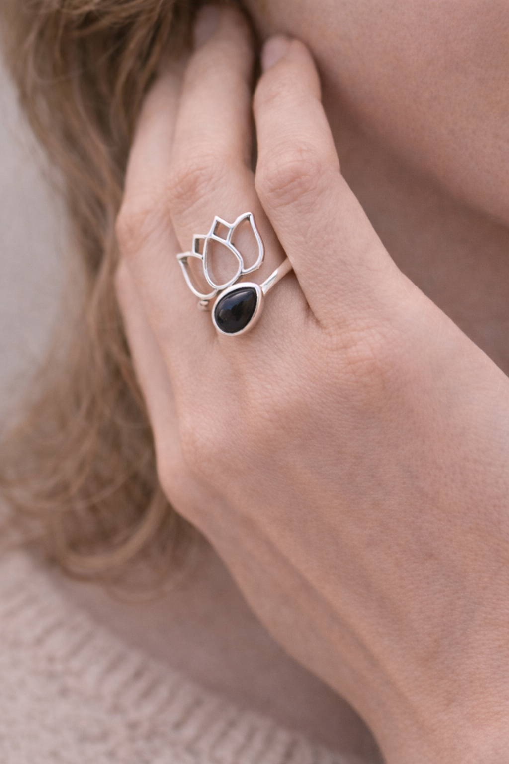 Bague Lotus Obsidienne & Argent 925, modèle Ancrage & Protection: doigt portant une bague argentée avec pierre noire et motif lotus.