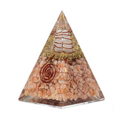 Pyramide en pierre d’orgonite rayonnante: couches de quartz et paillettes dorées avec spirales rouges décoratives, symbole solaire.