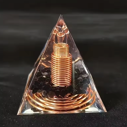 Pyramide en verre transparente Orgonite Bouclier Noir – Obsidienne avec spirale cuivrée au centre et amas noir brillant au bas.