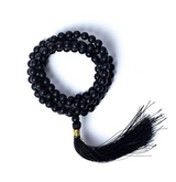 Mala de 108 perles en onyx noir, chaîne lustrée avec fermoir doré et Pompon noir, présentation en spirale.