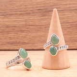 Bague Souffle de Renouveau – Aventurine verte et argent 925, devant un support en bois avec (3 bagues visibles) motifs argentés et pierres vertes.