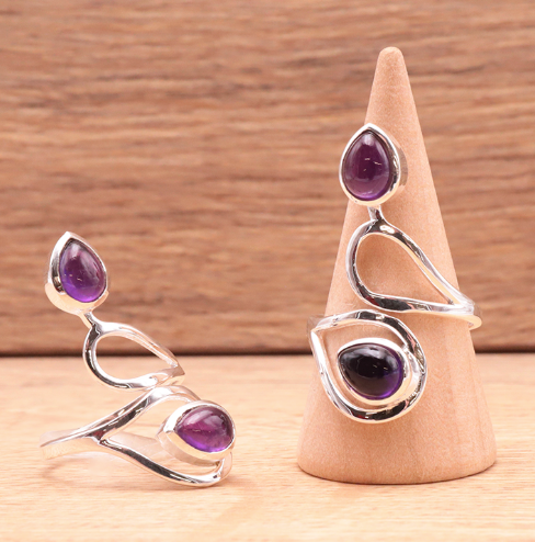 Bague en argent 925 avec améthystes violet profondes, design moderne et délicat sur supports en bois. Bague Voile de Sérénité Améthyste & Argent 925.