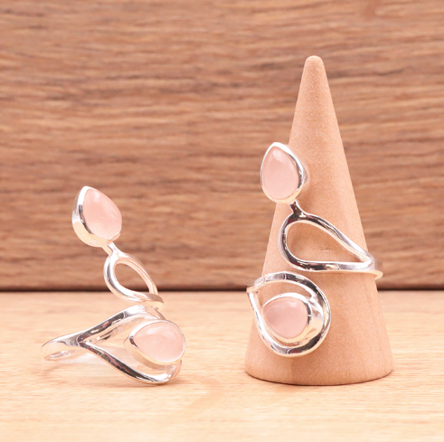 Bague et boucles d’oreilles argentées, motifs cœurs gravitant autour d’éclats quartz rose, présentation sur support conique.