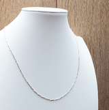 Chaîne Clarté Éternelle – Maille Épi en Argent 925 élégante portée sur un bustier blanc.