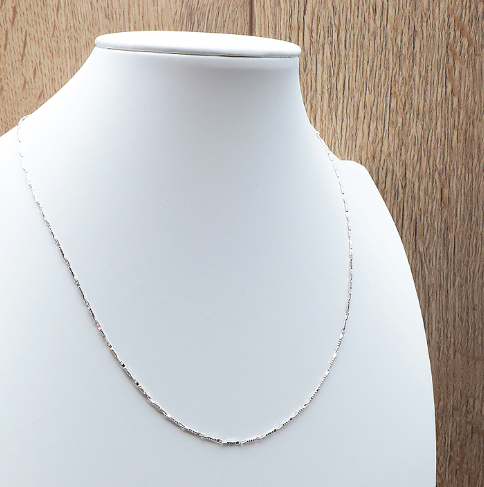 Chaîne Clarté Éternelle – Maille Épi en Argent 925 élégante portée sur un bustier blanc.