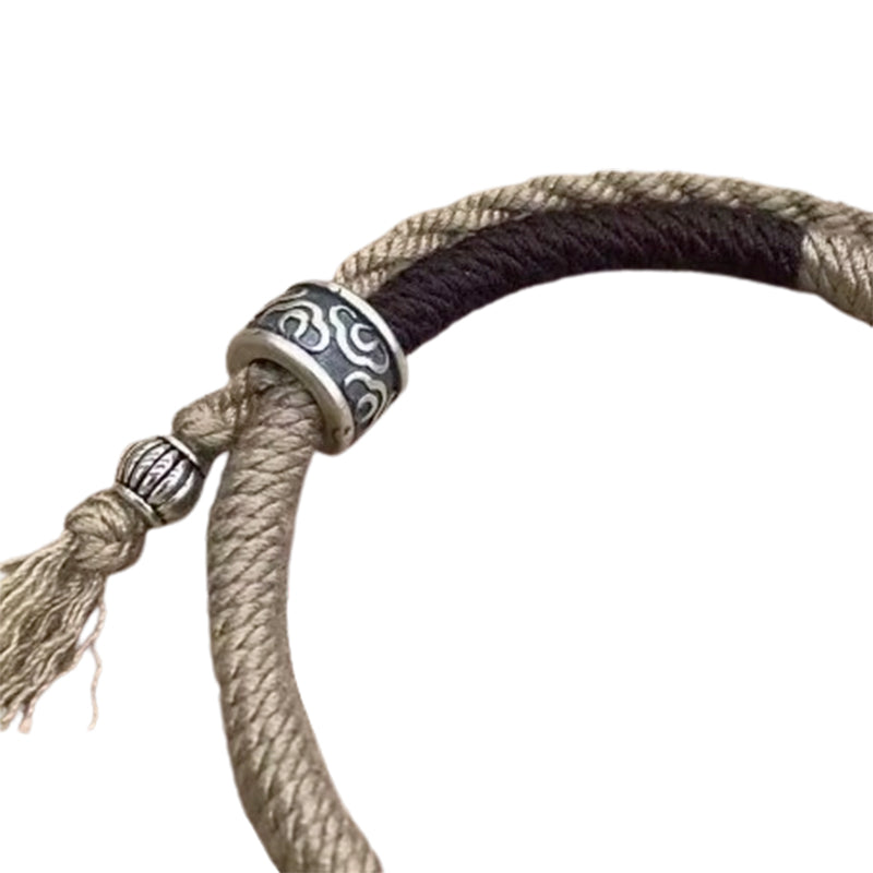 Bracelet Cercle Du Bonheur : cordon beige et noir avec fermoir argenté à motif, nœud et pendentif torsadé.