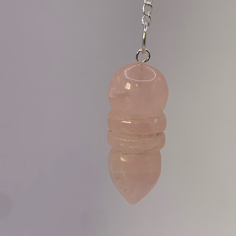 Pendule Egyptien en Quartz Rose en pendentif, chaîne et pièces nacrées visibles sur fond clair.